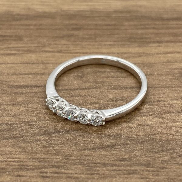 A three stone diamond ring on a wooden table.