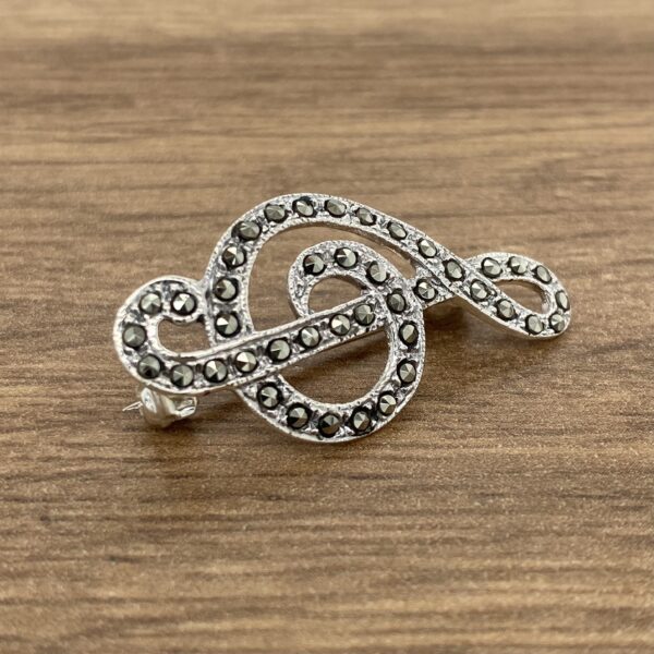 A silver musical note brooch with black diamonds.