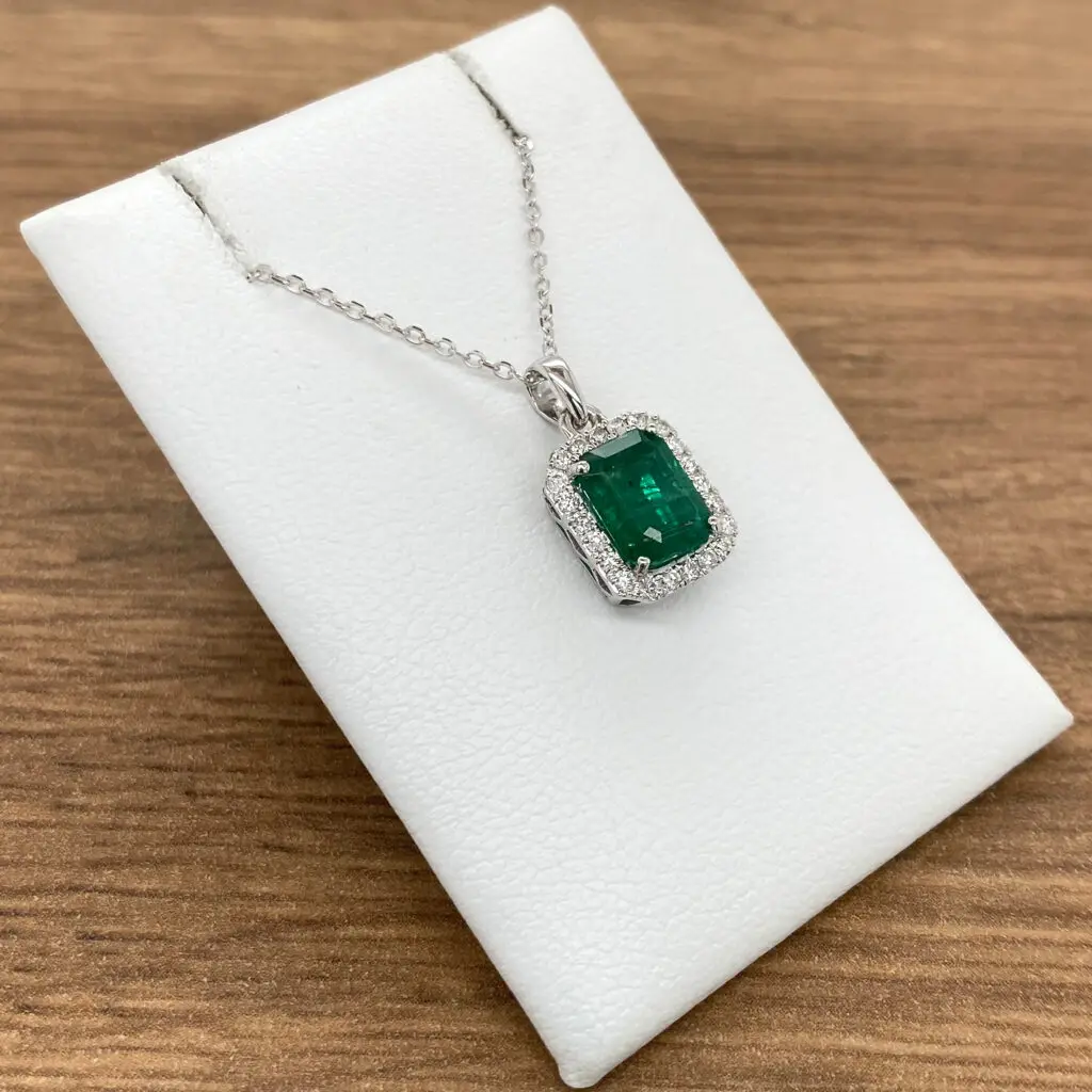 An emerald and diamond necklace on a white background.
