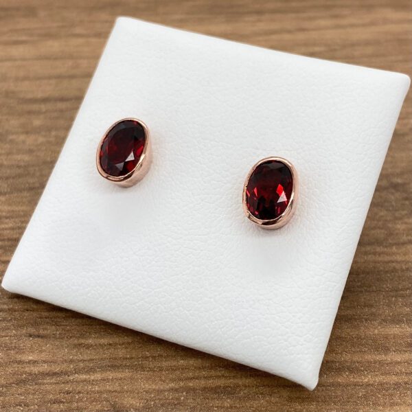 Red gemstone earrings in rose gold setting.