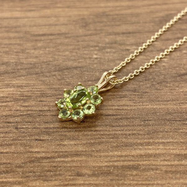 Gold necklace with green gemstone pendant.