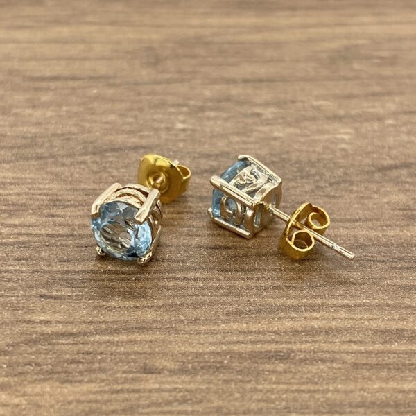 Pair of gold stud earrings with blue stones.