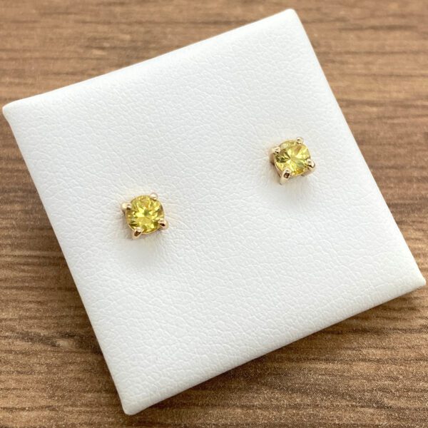 Yellow gemstone stud earrings on white background.