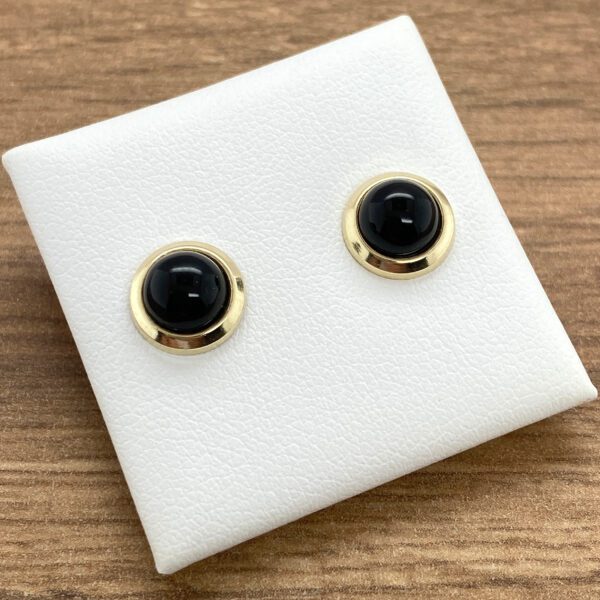 A pair of black onyx stud earrings on a white background.