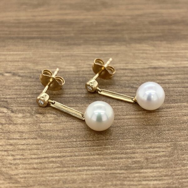 Gold pearl earrings with diamond accents.