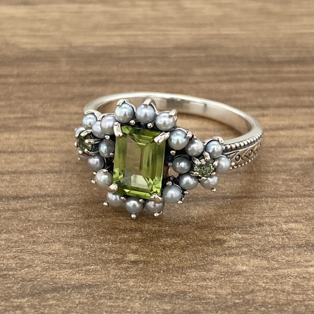 Silver ring with green gemstone and pearls.