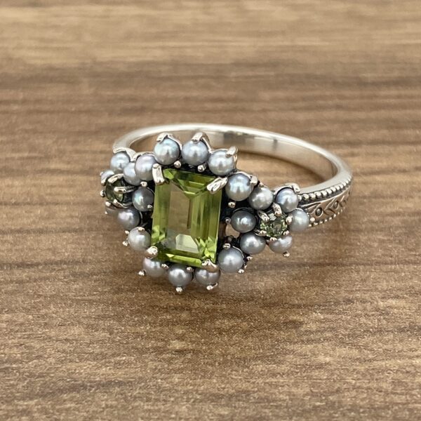 Silver ring with green gemstone and pearls.