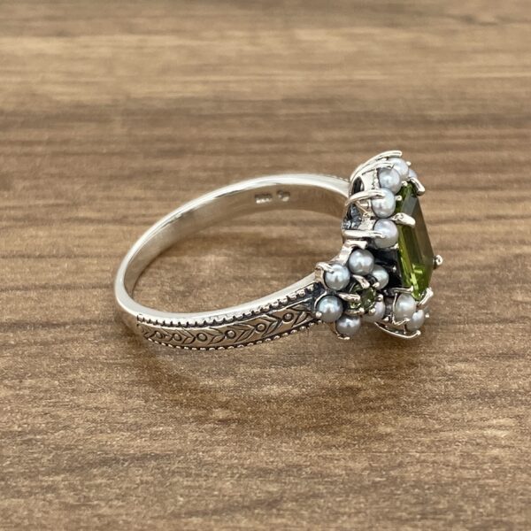 Silver ring with green gemstone and pearls.