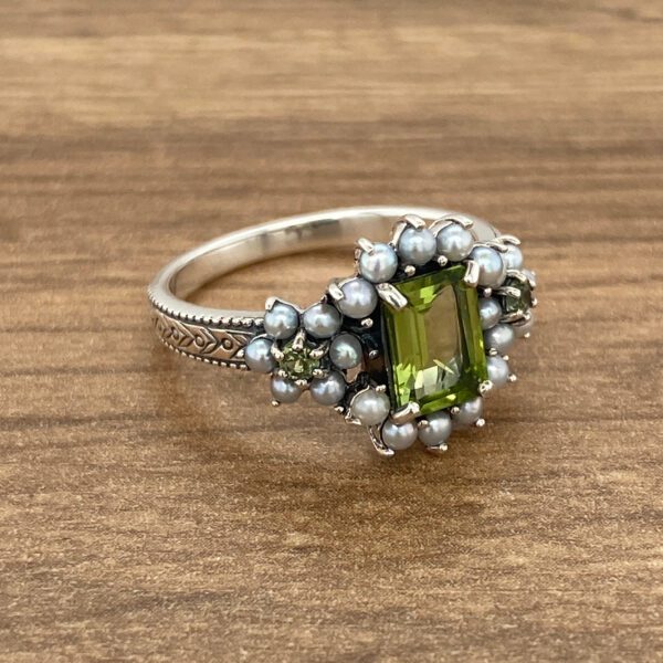 Silver ring with green stone and pearls.