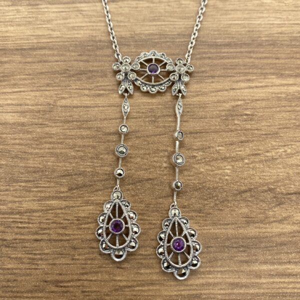 Silver necklace with purple gemstone drops.