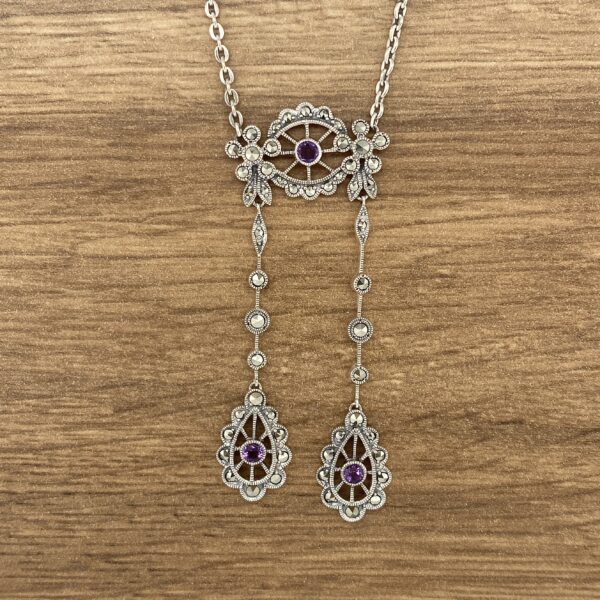 Silver necklace with purple gemstone drops.