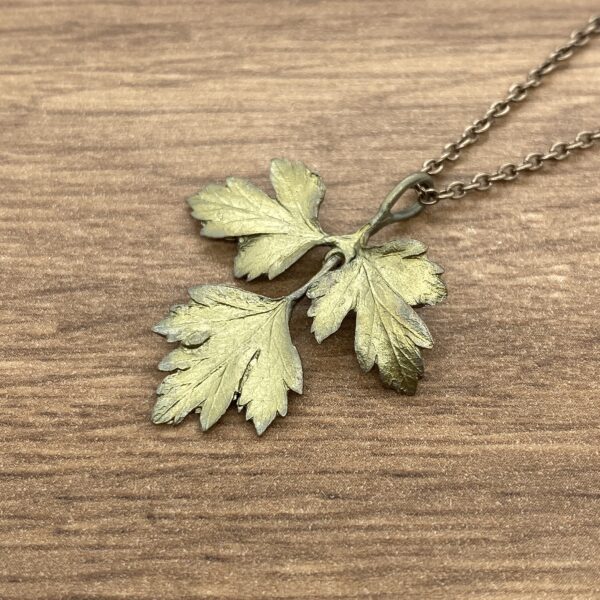 A gold leaf pendant on a wooden table.