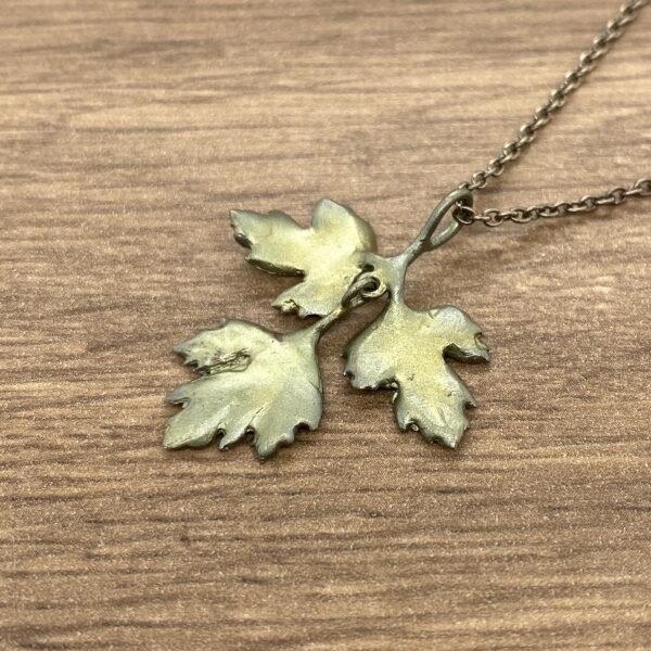 A gold leaf pendant on a wooden table.