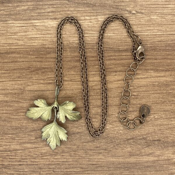 A gold leaf pendant on a wooden table.