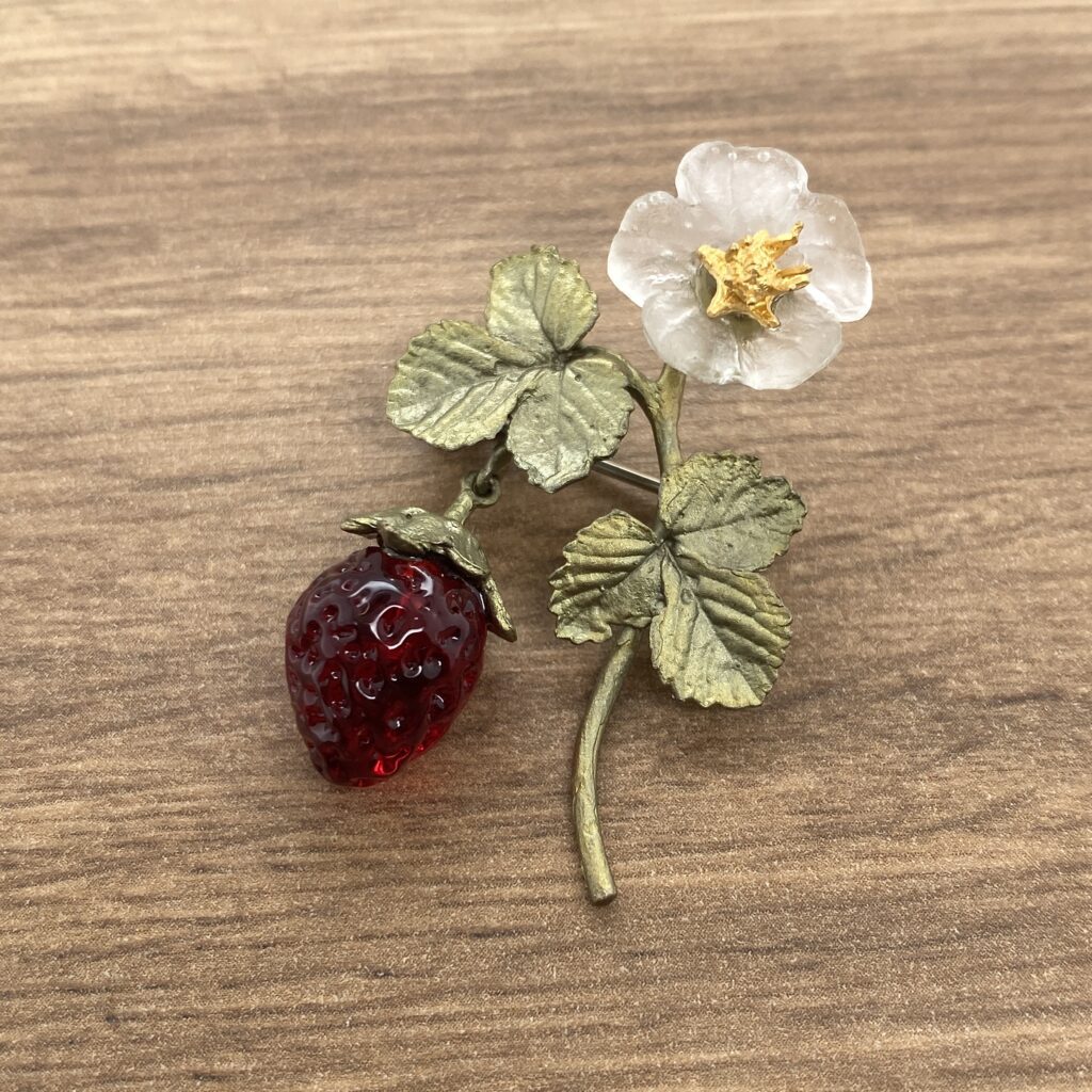 A brooch with a strawberry and a flower.