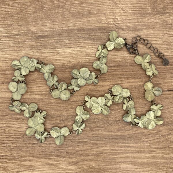 A green leaf necklace on a wooden table.