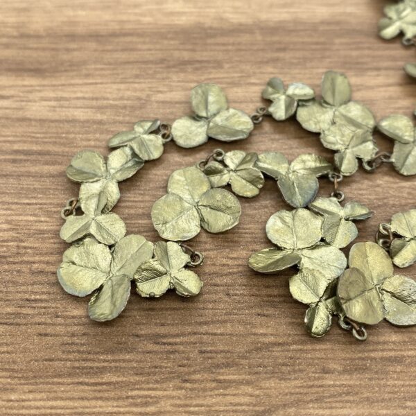 A green leaf necklace on a wooden table.
