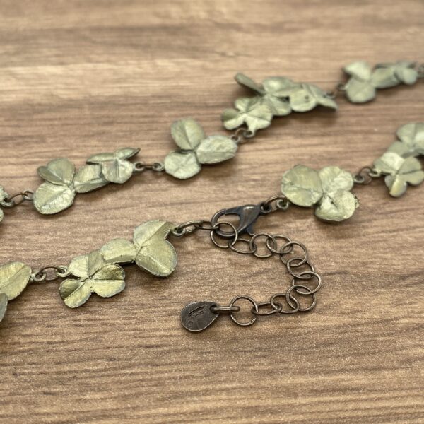 A green leaf necklace on a wooden table.