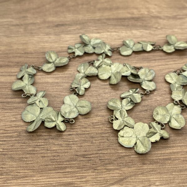 A green leaf necklace on a wooden table.
