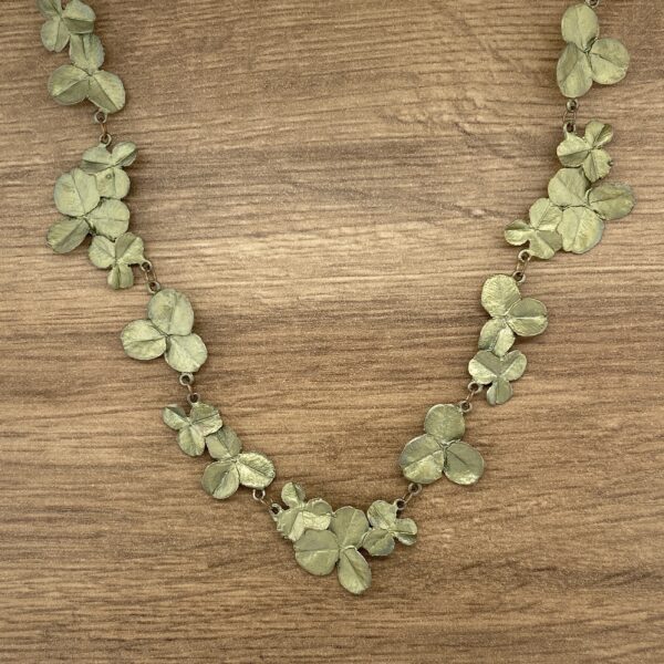 A green leaf necklace on a wooden table.