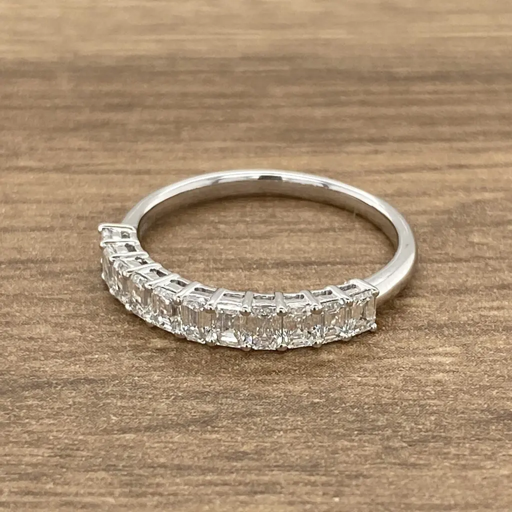 A princess cut diamond ring on a wooden table.