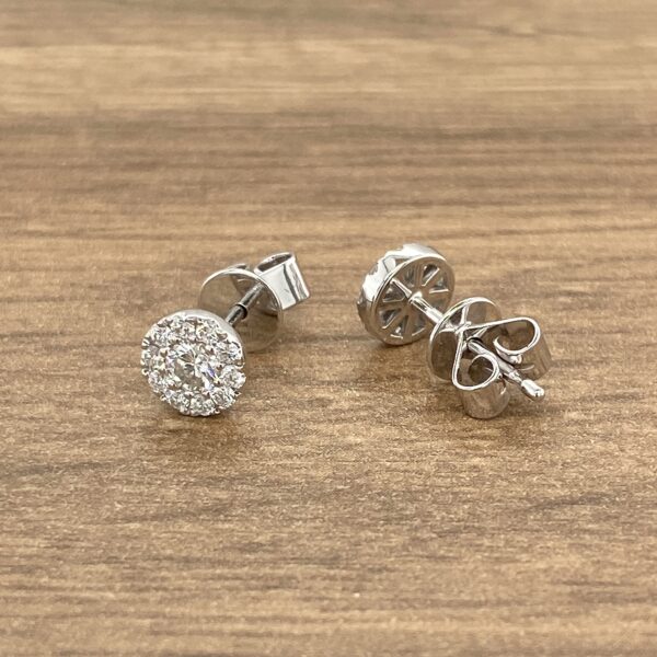 Diamond halo stud earrings on wood.