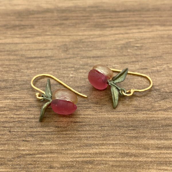 A pair of pink glass earrings on a wooden table.