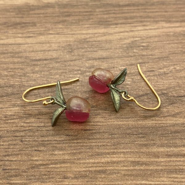 Gold peach earrings with green leaves.