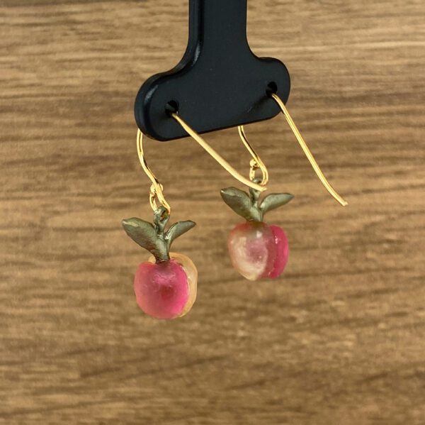 Gold peach earrings with green leaves.