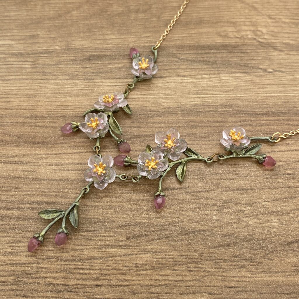 Gold necklace with pink and white flowers.