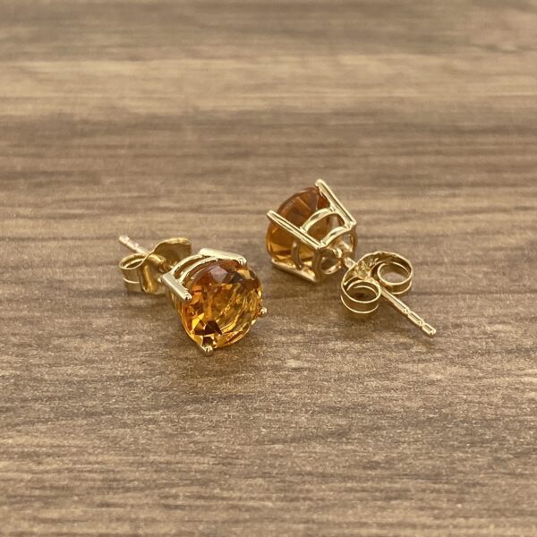 Gold earrings with orange gemstones.