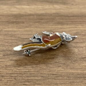 A Silver & Marcasite Enamel Fox Brooch on a wooden table.