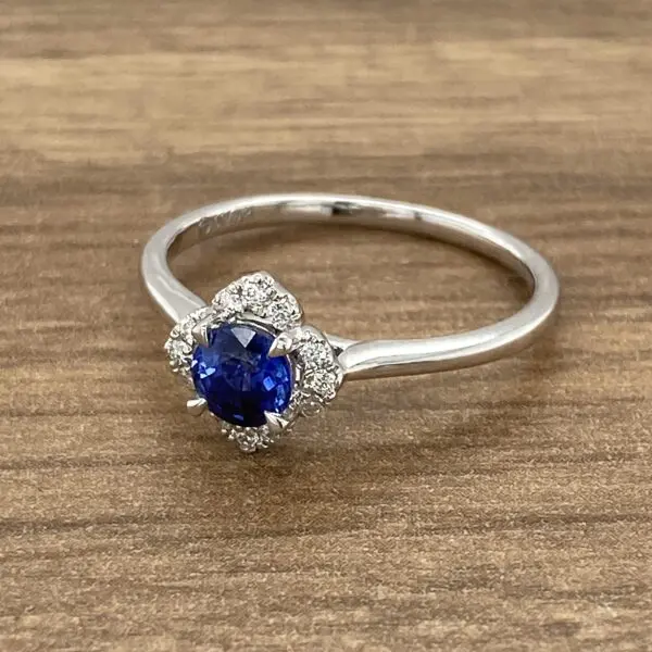 A sapphire and diamond ring on a wooden table.