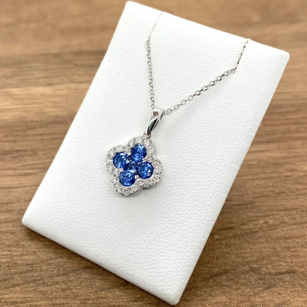 A blue sapphire and diamond pendant on a white background.