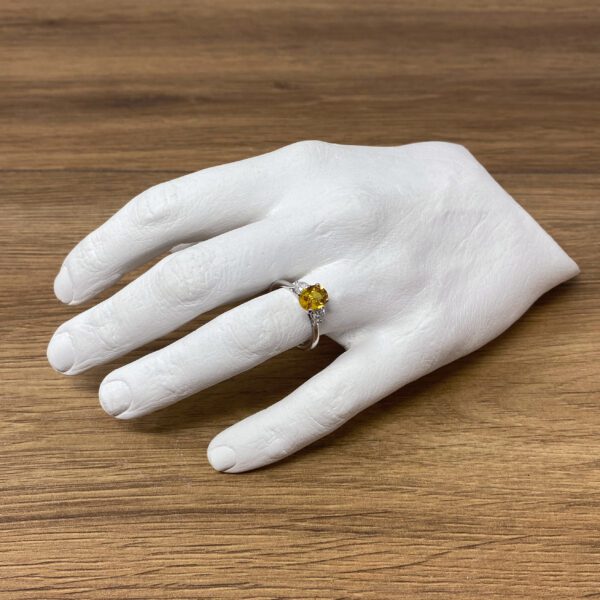 Yellow gemstone ring on a white hand.