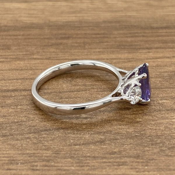 An amethyst and diamond ring on a wooden table.