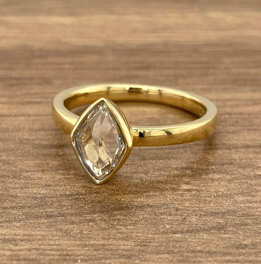 A gold ring with a white topaz stone.