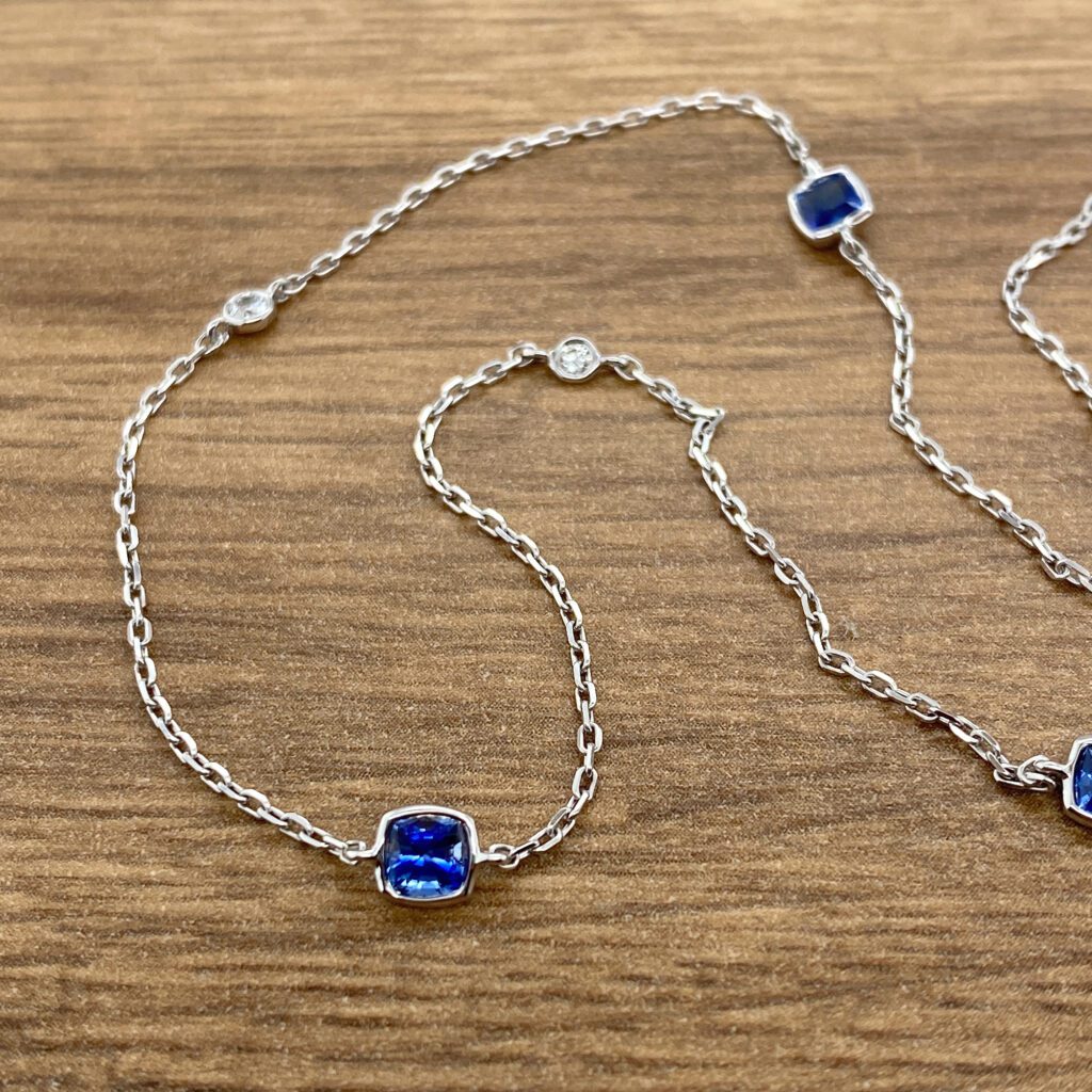 A blue sapphire and diamond necklace on a wooden table.