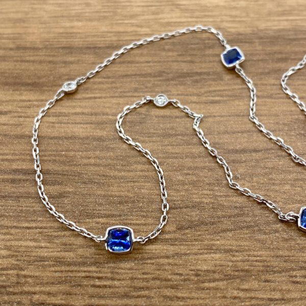 A blue sapphire and diamond necklace on a wooden table.