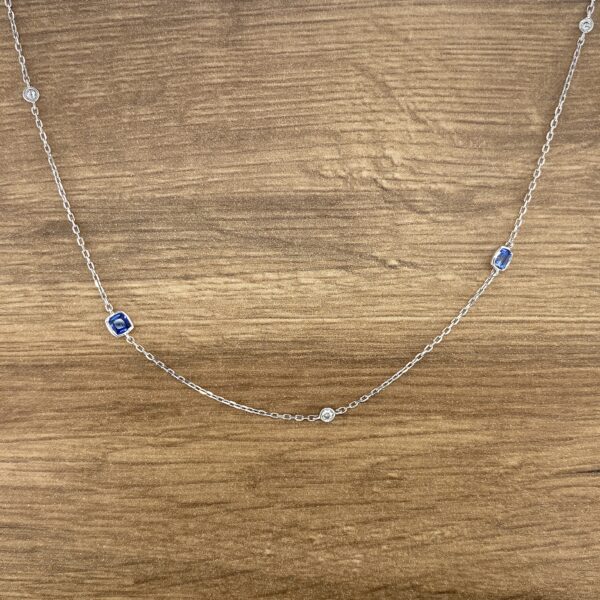 Silver chain necklace with blue gemstones.