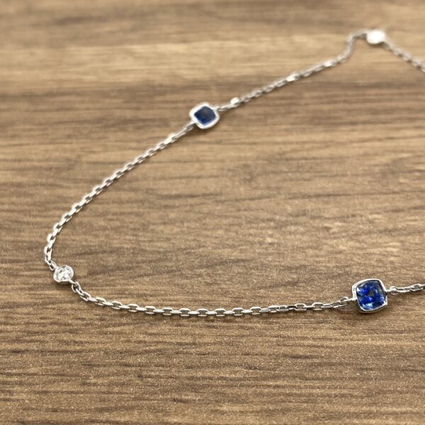 Silver chain necklace with blue gemstones.