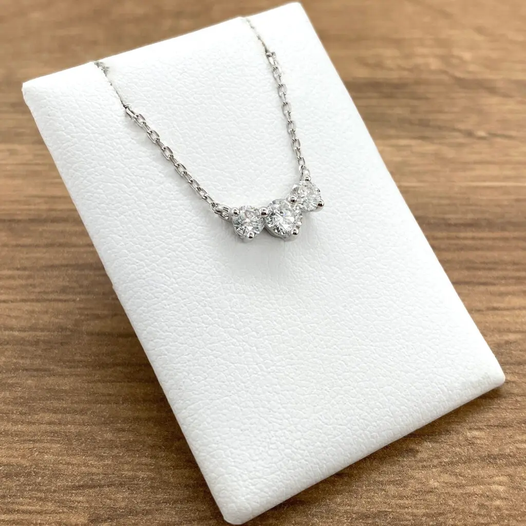 A necklace with three diamonds on top of a white box.