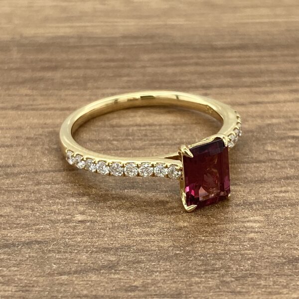 Gold ring with a red gemstone and diamonds.