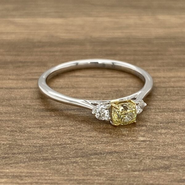 An engagement ring with a cushion cut yellow diamond.