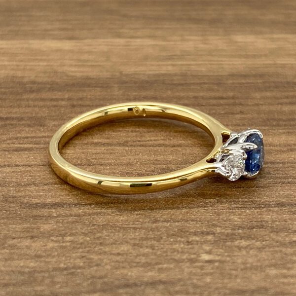 A sapphire and diamond ring on a wooden table.