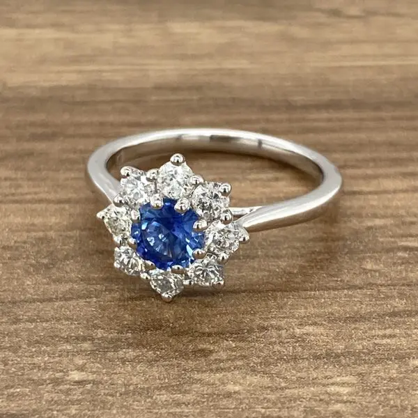 A sapphire and diamond ring on a wooden table.