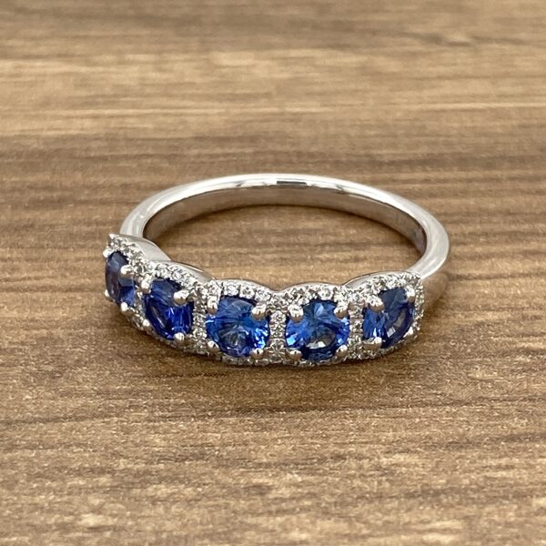 A sapphire and diamond ring on a wooden table.