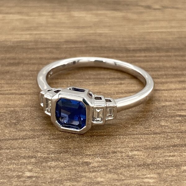 A sapphire and diamond ring on a wooden table.