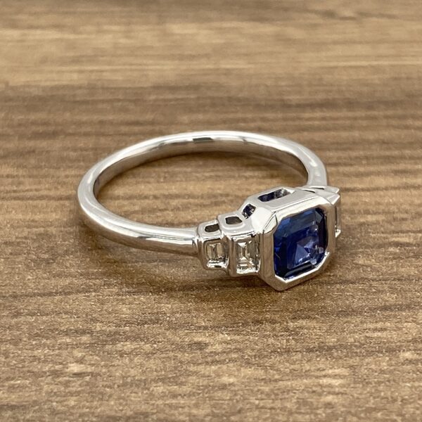 A sapphire and diamond ring on a wooden table.