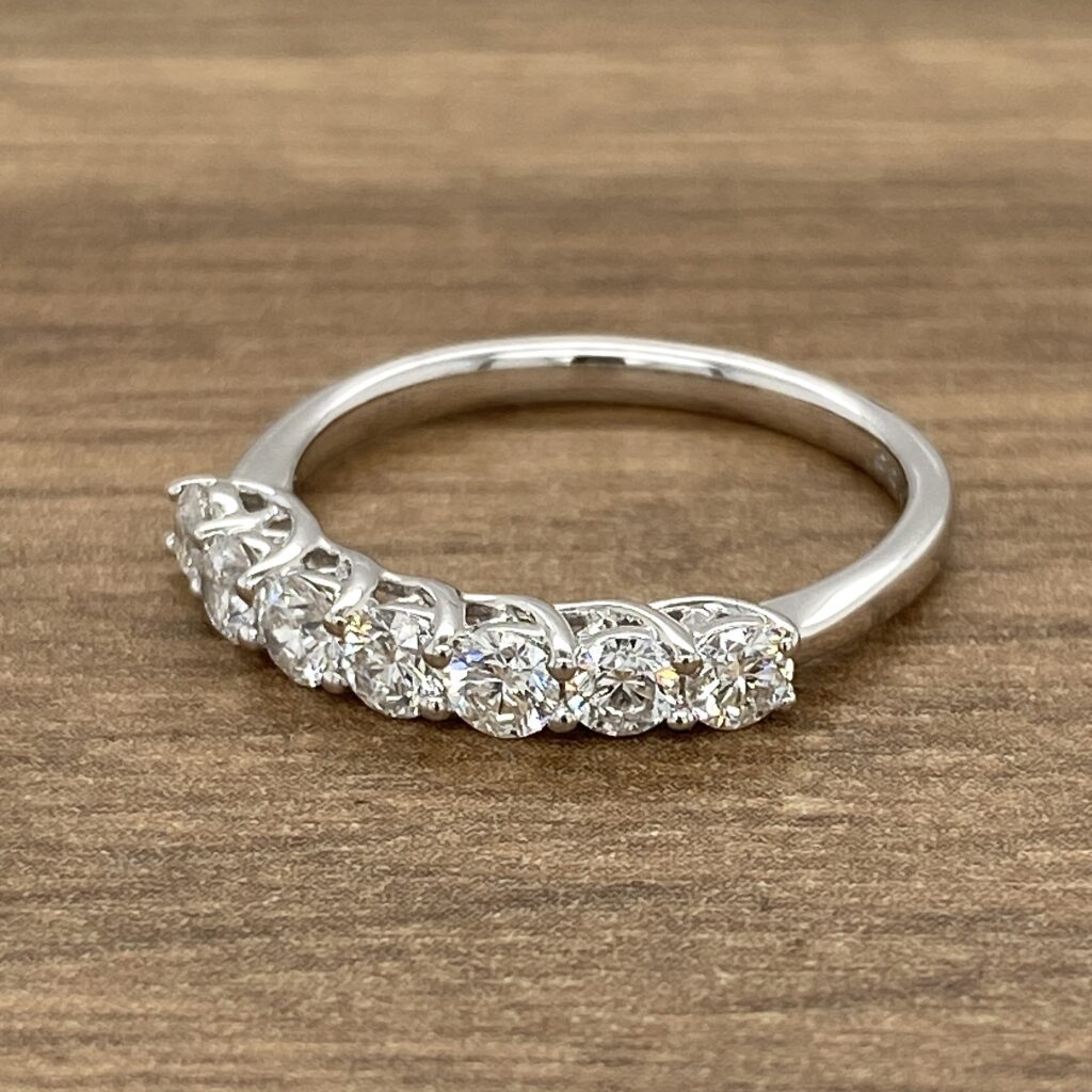 A white gold five stone diamond ring on a wooden background.